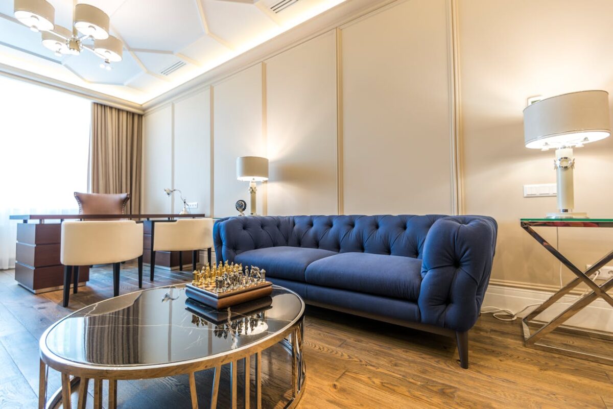 gallery-03 Bright modern living room featuring a blue couch, elegant decor, and ample natural light.