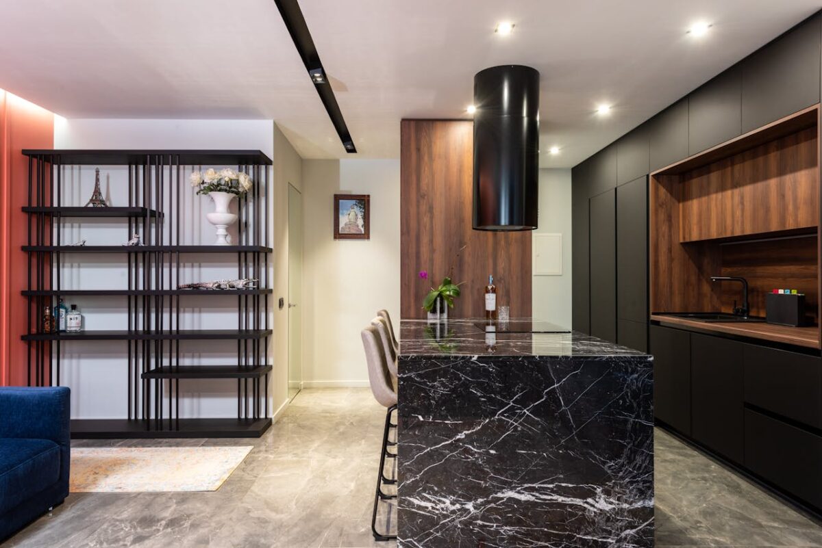 gallery-01 Modern kitchen interior with black marble island and wooden cabinets, featuring a sleek design.