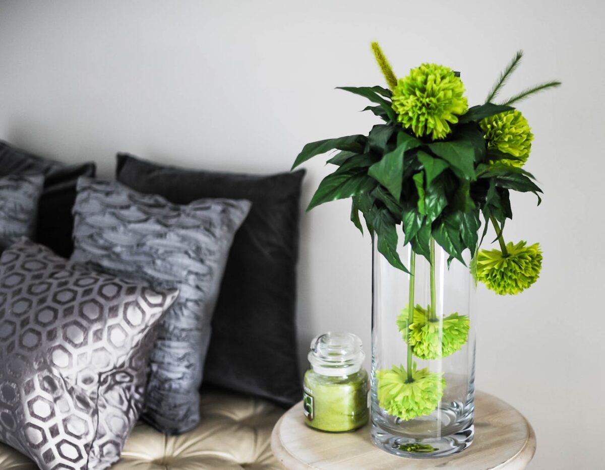 hero Sophisticated room decor featuring green flowers in a vase, soft pillows, and chic glass jar.